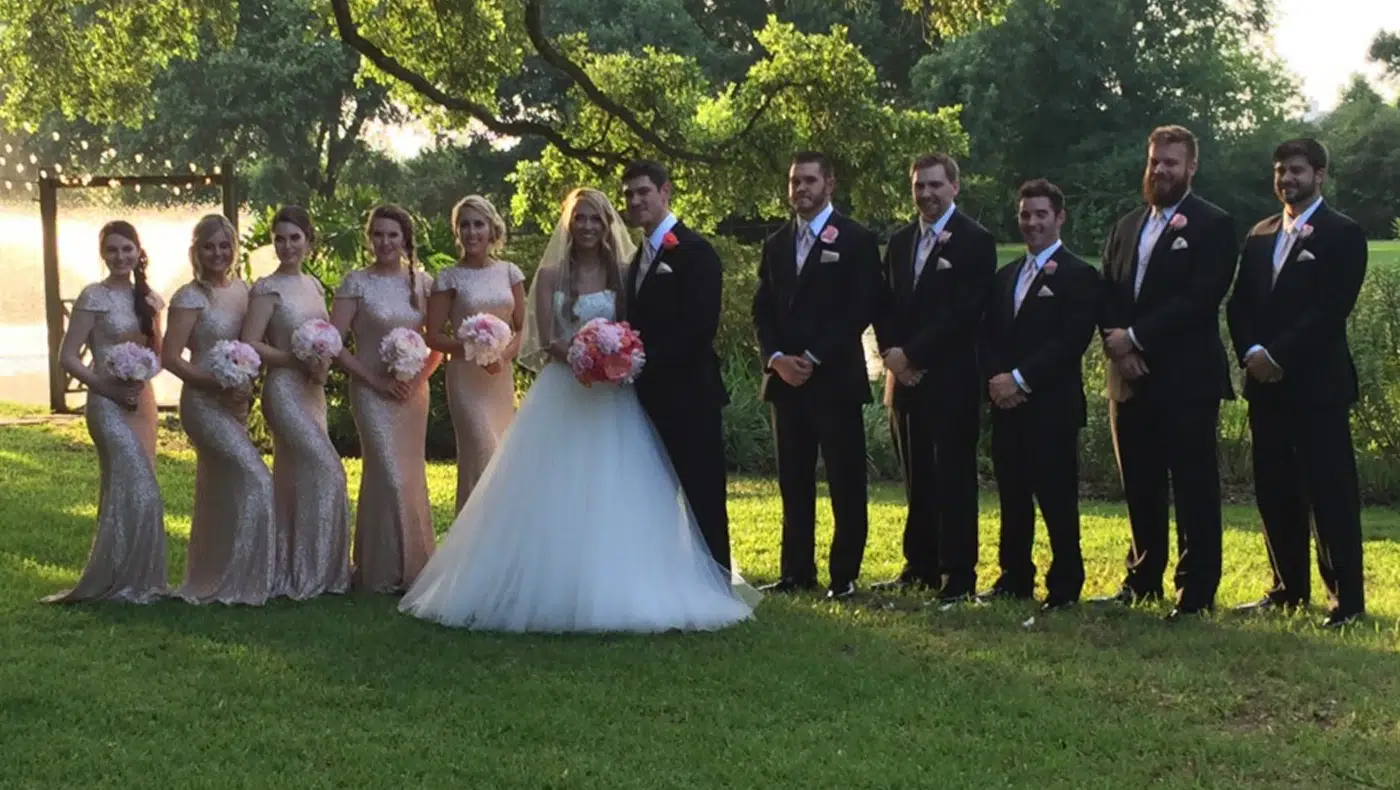 Bride and groom stand with a group posing in the park