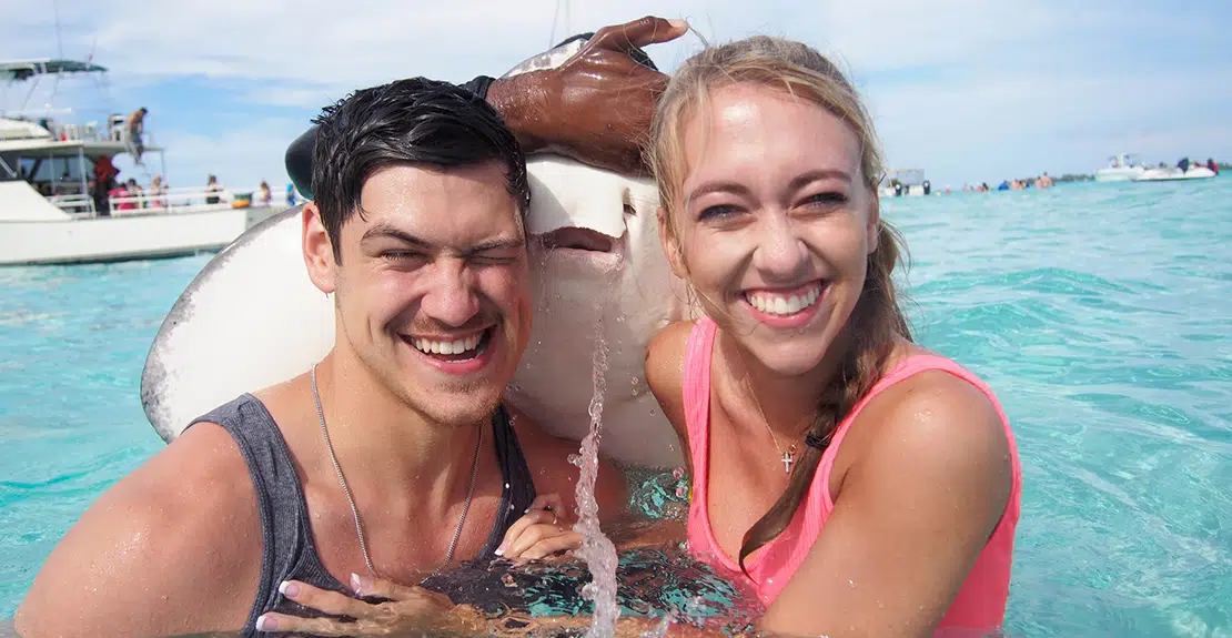 Man and woman pose with a stingray in the ocean