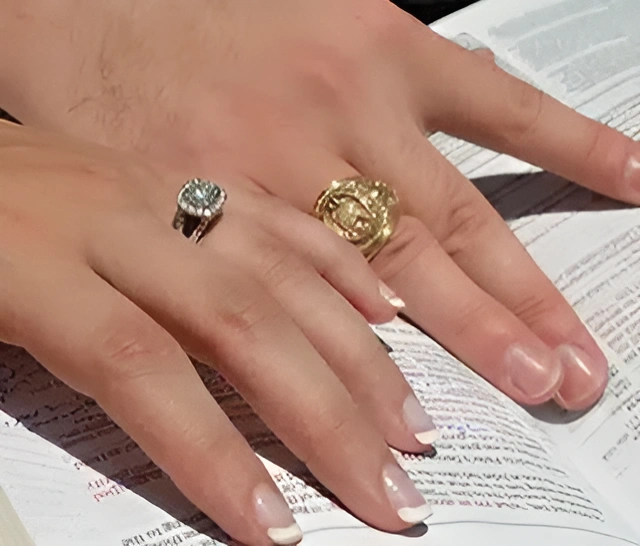 A couple show off their engagement rings, close of of hands with rings