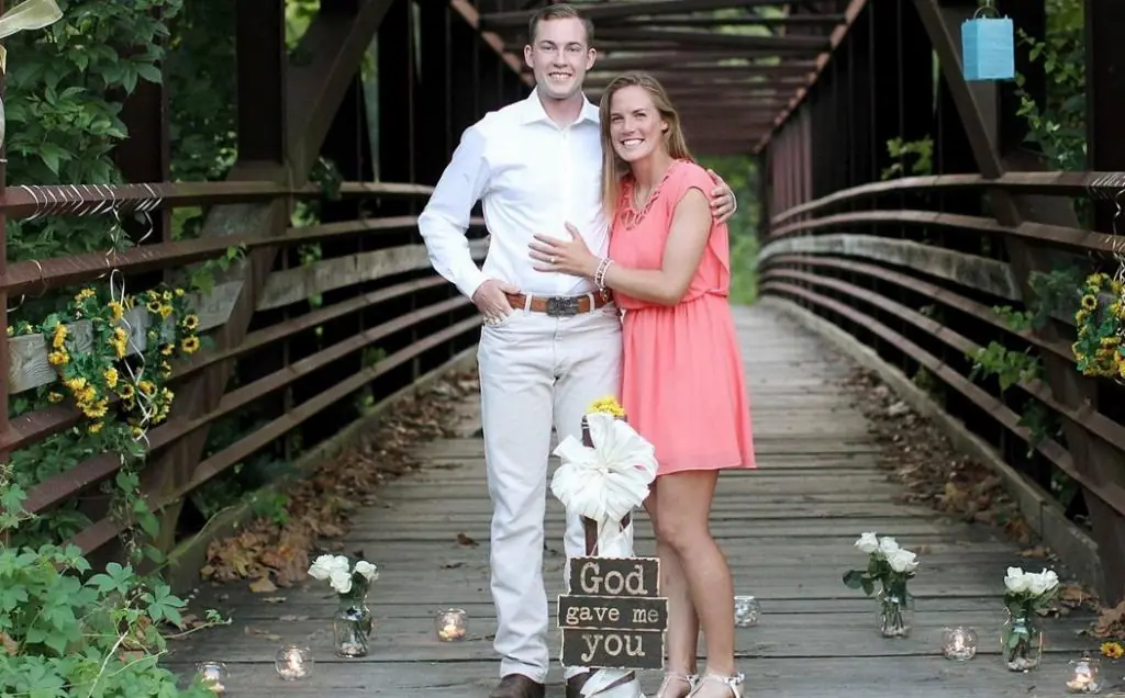 Newlyweds stand on a bridge with flowers around them