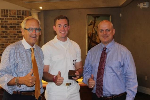 Three men pose with thumbs up inside a room, the man in the middle wearing all white