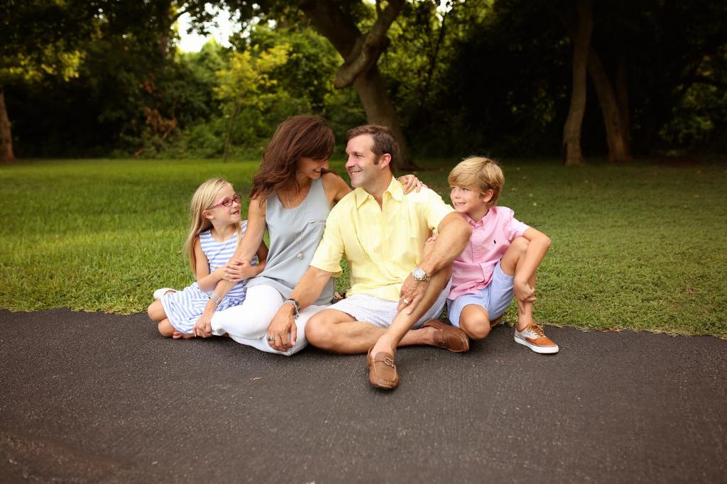 Family sits together smiling on the pavement