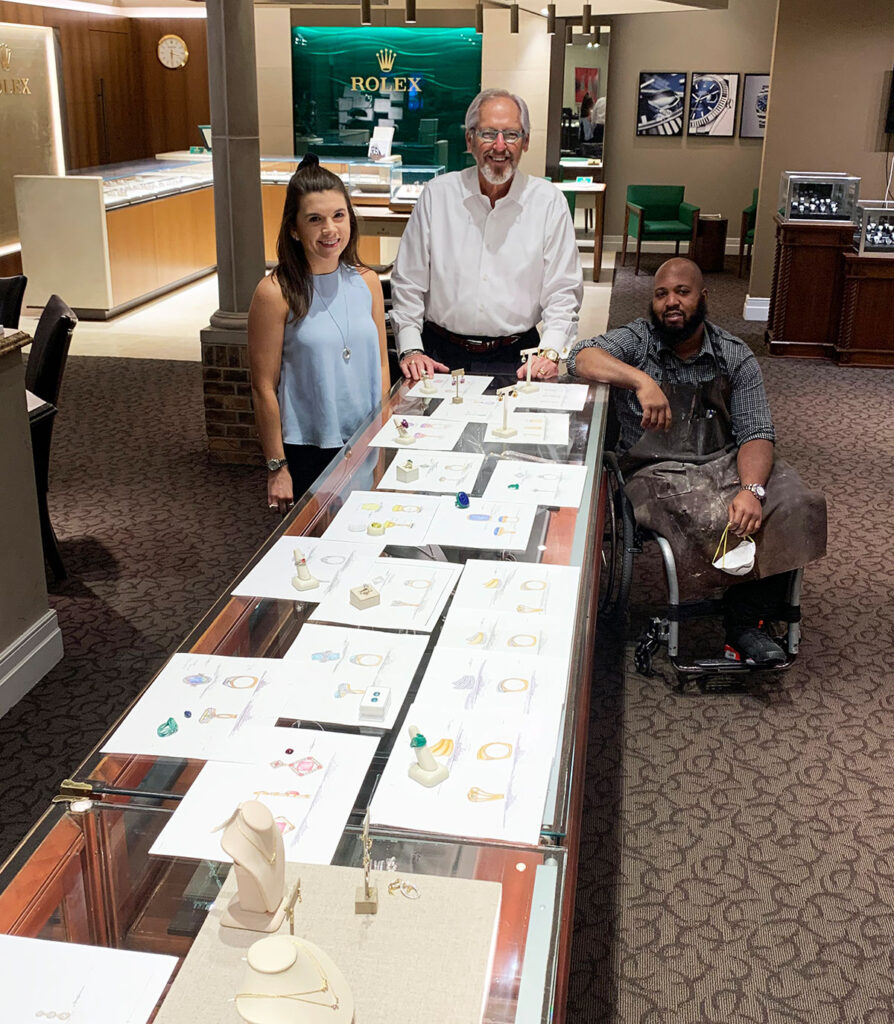 David Gardner and staff with custom drawings of jewelry on the store counter.