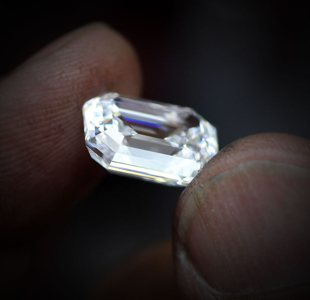 Loose natural diamond being held between two fingers.