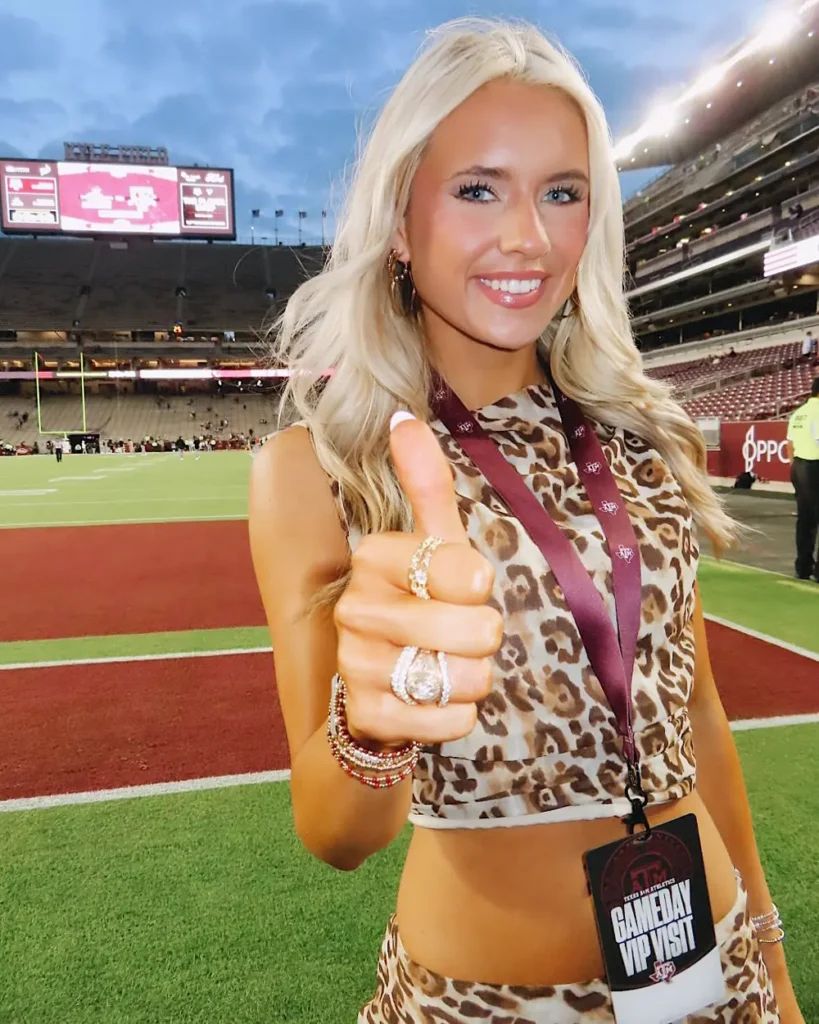 Aggie Graduate smiling with her class ring and RW Fine RingWrap at the baseball field
